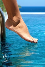 Huésped comprobando la temperatura del agua de la piscina climatizada